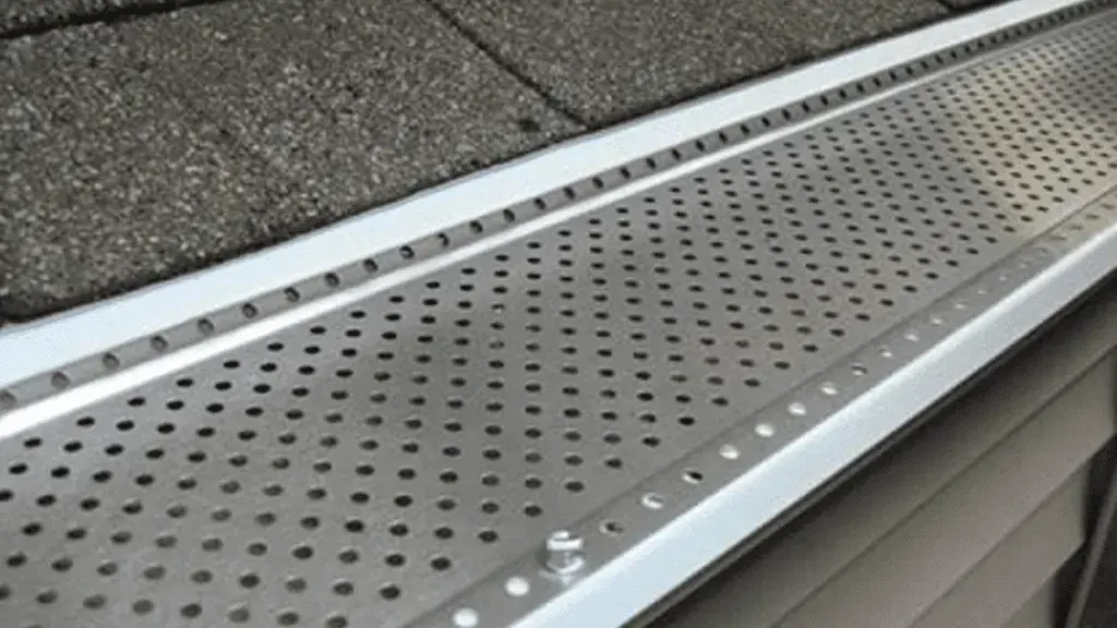 Perforated gutter guard installed along a shingle roofline